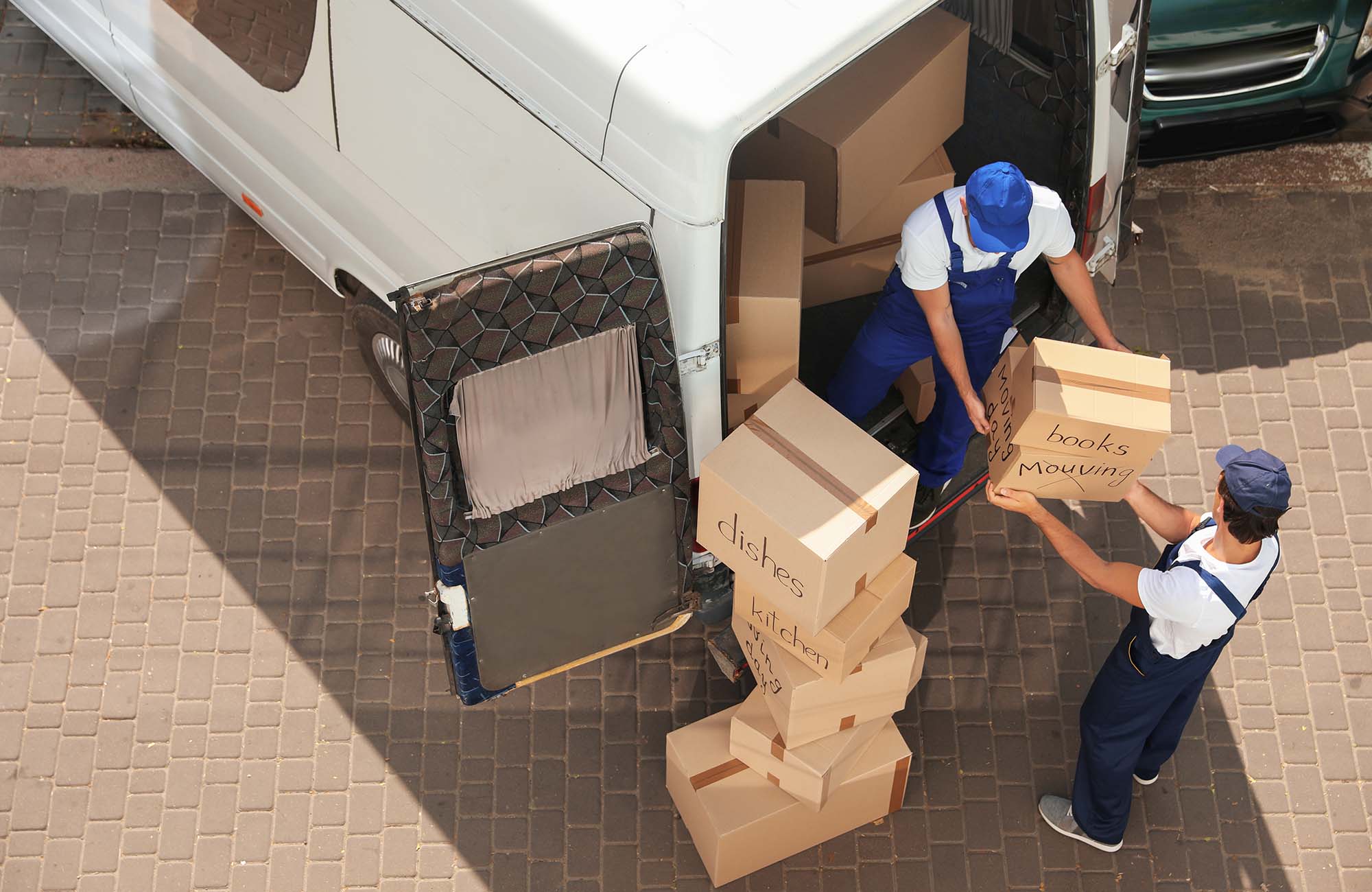 Male movers unloading boxes from van outdoors, above view