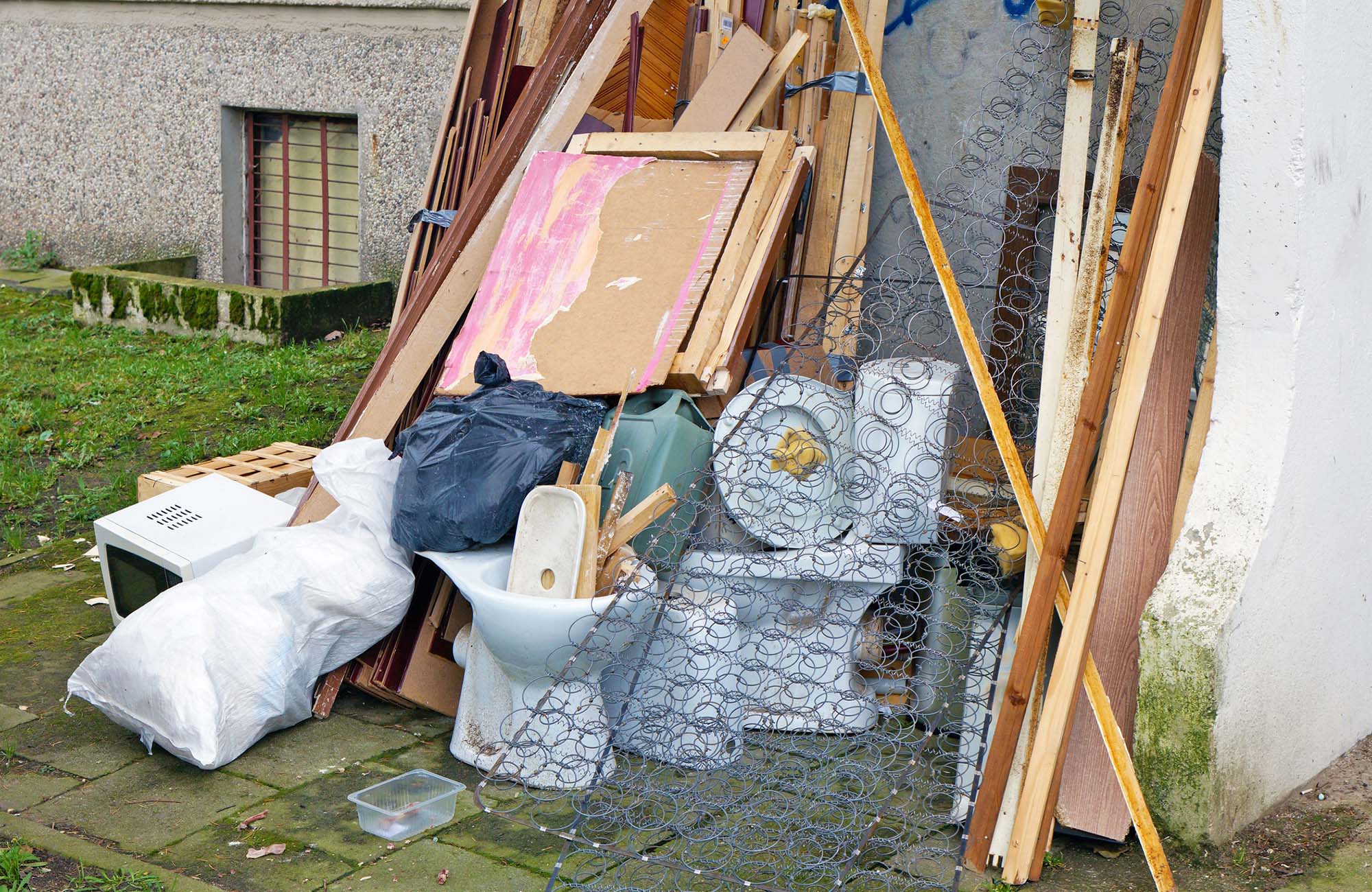 Old broken furniture, old ceramic toilets and microwave at the garbage dump near the apartment building